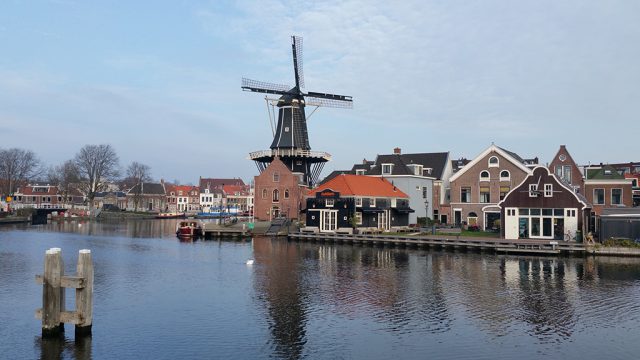 a river with houses and a windmill