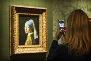 A woman making a picture of a painting with a girl with a pearl earring
