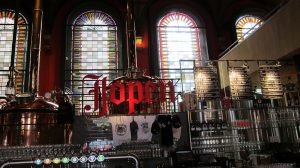 A neon sign of Jopen, with bottles of beer and church windows at the background