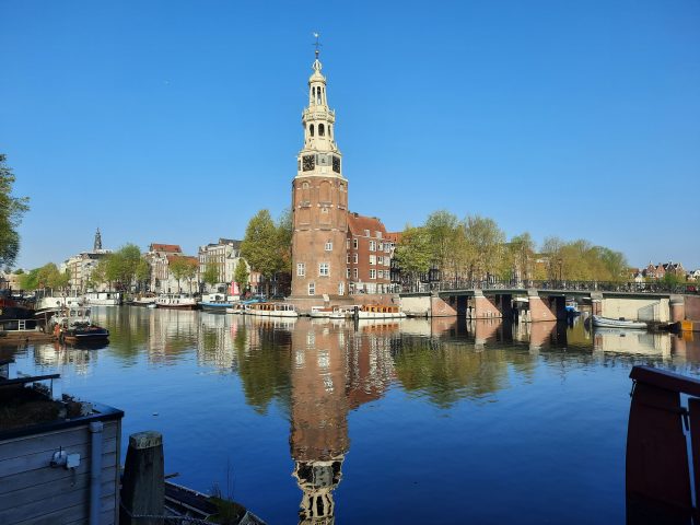 medieval tower with its reflection in the water under a clear blue sky