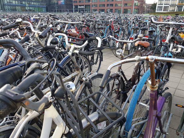 Thousands of bicylces parked on a square with buildings at the background