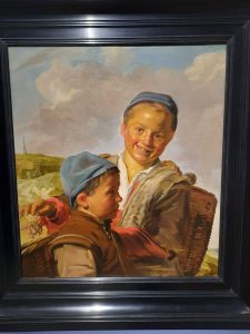 a painting by Frans Hals of two smiling boys under a couded sky
