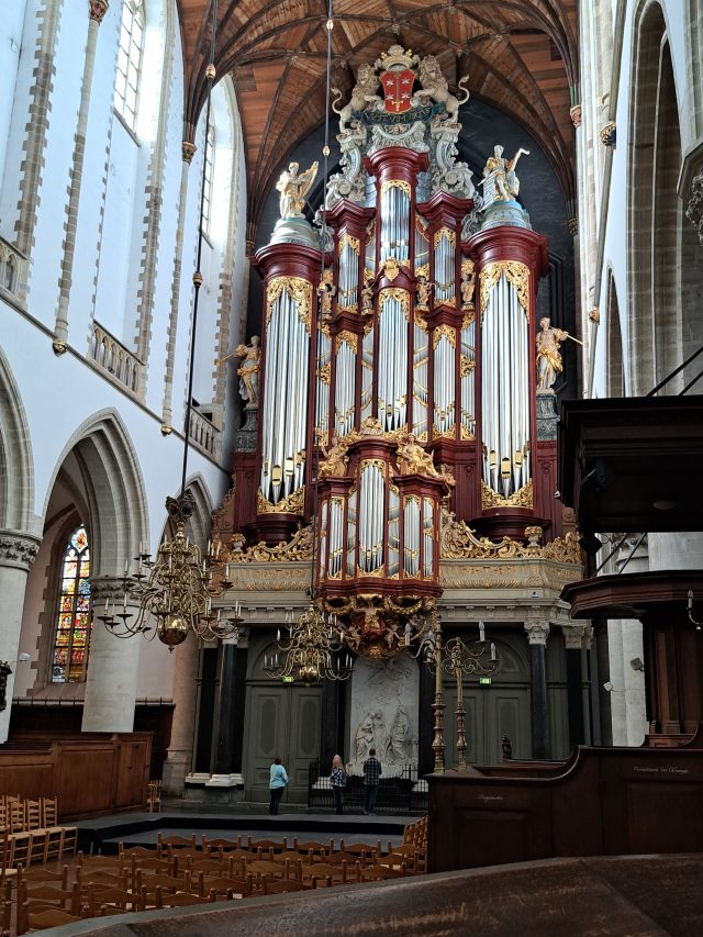 a huge organ in an old church with people in front