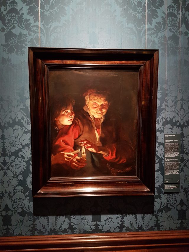 a painting in a frame on a wall, with an old woman, a young boy and a lit candle