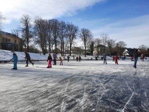Adults and children ice skating on a frozen canal