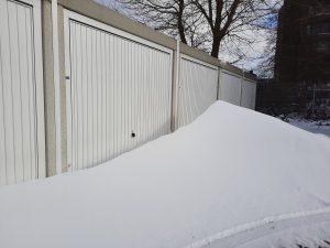 A pile of snow in front of a car garage door