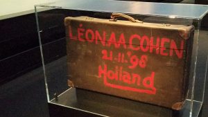 A suitcase in a glass box with a name and date written on it