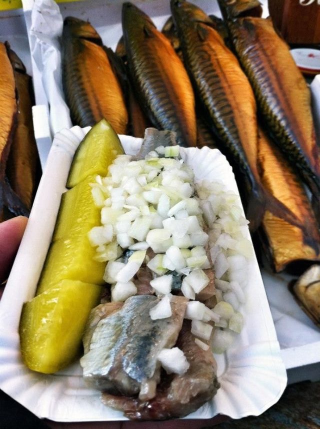 Pieces of fish with onion and pickles on a paper plate