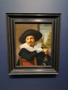 a painting of a man with an old black hat, leaning backwards on a chair
